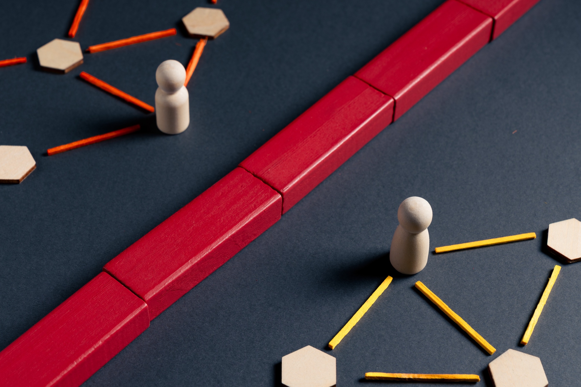 Wooden figures and network nodes separated by a red barrier - disconnected business systems